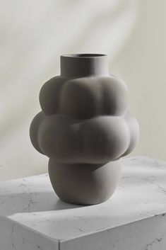 a gray vase sitting on top of a white table