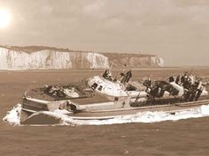 an old photo of a boat full of people in the water with cliffs in the background