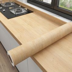 a kitchen counter with a roll of wood paper on top of it next to a window