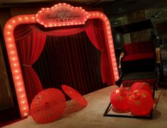 a red stage set up with umbrellas, chairs and lights on the floor in front of it