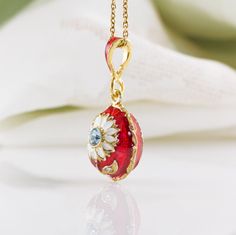 "A small pendant with the daisy flower, enameled and 24 K gold plated over solid sterling silver, created in our NJ shop in the spirit and tradition of Faberge jewelry eggs. The surface of the piece is covered by rich red enamel, underlining a cute white flower with a gentle sky blue Swarovski crystal at the center. Clear Swarovski crystals are set in the leaves. The egg is pretty small - about 0.5\" (14 mm ) long - and will be appropriate for a girl as well as a grown up woman. It comes with 18 Yellow Gold Enamel Jewelry With Flower Charm, Yellow Gold Enamel Flower Pendant Jewelry, Enamel Hallmarked Oval Pendant Necklace, Flower Shaped Polished Jewelry As Gift, Flower Shape Jewelry As A Gift With Polished Finish, Flower-shaped Polished Jewelry Gift, Flower Shaped Jewelry With Polished Finish For Gift, Flower Shaped Polished Finish Jewelry As Gift, Flower Shaped Polished Finish Jewelry For Gift