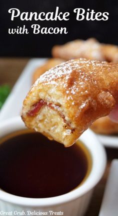 a hand holding up a pastry with bacon in it and dipping sauce on the side