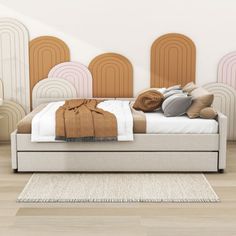 a bed sitting on top of a wooden floor next to a wall with art work