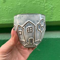 a hand holding a cup with a house on it