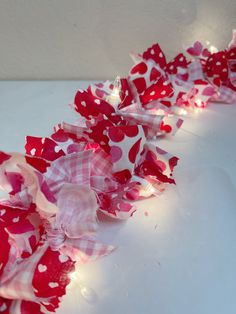 a red and white ribbon with hearts on it is sitting on a table next to some lights