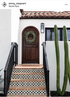 a house with a cactus next to it and stairs leading up to the front door