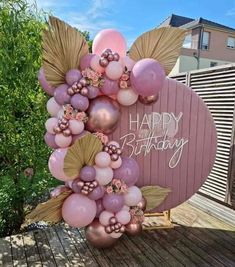 a happy birthday balloon arch with balloons and flowers