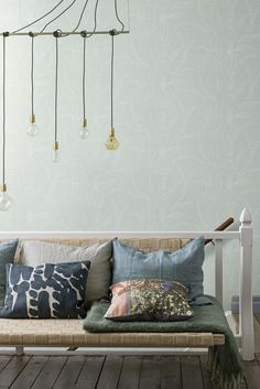 a couch with many pillows on it in front of a wall mounted chandelier