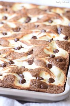 a close up of a cake with chocolate chips and cream on it in a pan