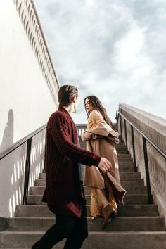 two people are walking up some stairs and one person is holding onto the handrail