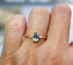 a woman's hand holding a ring with a blue topazte and diamond