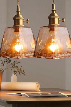 two clear glass pendant lights hanging over a wooden table