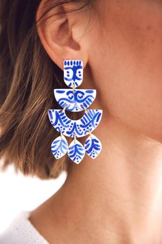 a woman wearing earrings with blue and white designs on it's earrings