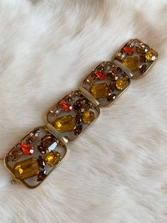 "Vintage 1940's statement signed Napier bracelet. Gold tone bracelet with amber, brown, and bright orange rhinestone crystals. Rhinestones are oval, circle, baguette, emerald, and tear drop cut. Bracelet in excellent condition with minor wear due to age. High quality and high shine rhinestones. Measurements Length: 6-3/4\" / Width: 1-1/2\" / Unless otherwise stated all vintage items are used and may have minor to moderate wear or discoloration considering the age of the item. Most items have bee Vintage Amber Rectangular Jewelry, Mid-century Metal Bracelet Jewelry, Elegant Orange Metal Bracelets, Vintage Orange Gemstone Jewelry, Elegant Orange Metal Bracelet, Retro Jeweled Bracelet For Formal Occasions, Retro Jeweled Bracelets For Formal Occasions, Vintage Orange Jewelry For Party, Retro Orange Jewelry For Party