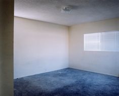 an empty room with blue carpet and white walls