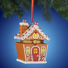 a christmas ornament hanging from a tree branch with a house on it's roof