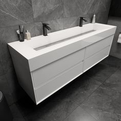 a white sink sitting next to two black faucets