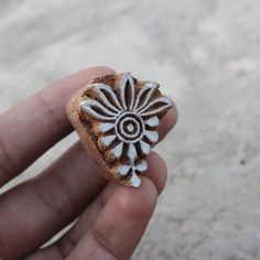 a hand holding a small piece of pottery in it's left hand, with white designs on the outside