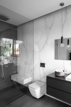 a bathroom with a toilet, sink and shower stall in black and white color scheme