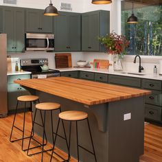 a kitchen with green cabinets and wooden counter tops