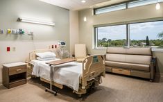 a hospital room with a bed, couch and window