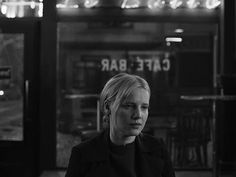 a black and white photo of a woman in front of a cafe