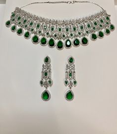 Enhance your outfit with our CZ American Diamond Necklace. The greenstones add a touch of elegance to any attire, from sarees to gowns and lehengas. Perfect as a gift, this necklace will elevate your style with its stunning design and sparkle. This jewellery set includes a necklace and matching earrings. Jewellery Care- Keep the jewellery dry, avoid contact with perfumes and water. Green Kundan Jewelry With Stones, Green Emerald Necklace Hand Set For Party, Dazzling Green Jewelry Set With Elegant Design, Festive Green Jewelry Sets With Stones, Festive Green Stone Jewelry Sets, Party Green Emerald Necklace Hand Set, Elegant Green Sets For Reception, Emerald Bollywood Jewelry As Gift, Emerald Jewelry With Stone Work For Celebration