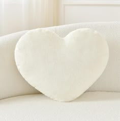 a white heart shaped pillow sitting on top of a couch