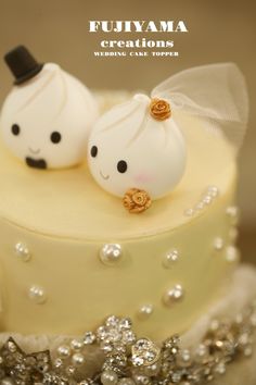 two wedding cake toppers sitting on top of a yellow and white frosted cake