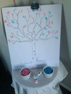 a white canvas with a tree painted on it and two paint bowls next to it