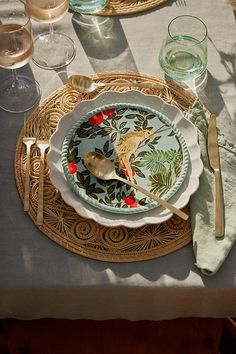 a table set with plates, silverware and wine glasses on top of the table