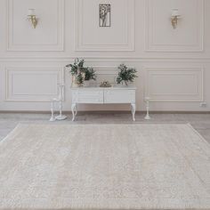 a white table sitting in the middle of a room with two planters on top of it