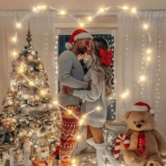 a man and woman are kissing in front of christmas trees with teddy bears around them