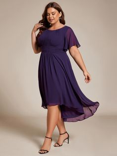 a woman in a purple dress poses for the camera with her hand on her hip