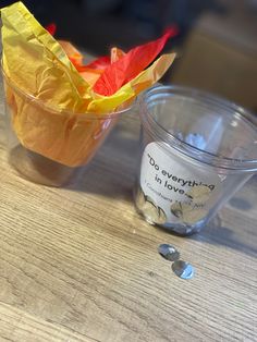 a plastic cup filled with food next to a paper boat on top of a wooden table