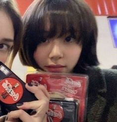 two young women holding up cell phones in their hands