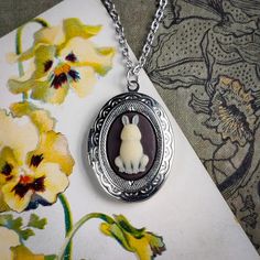 a necklace with an image of a rabbit in the center and flowers around it on a floral background