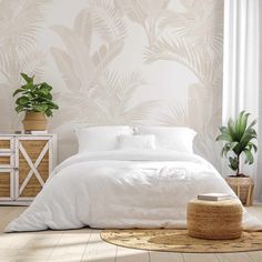 a white bed sitting in a bedroom next to a plant on top of a table