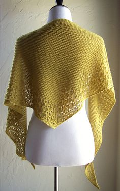 a yellow knitted shawl sitting on top of a white mannequin