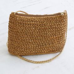 This fabulous shoulder bag is made of braided capim dourado or golden grass native to the Jalapao State Park in Brazil. Designed by Wagner and Cassia of Brazil artisans stitch together rows of braided grass which is naturally golden in color to form the outside of the bag. The single compartment is lined with satin in a golden color and closes with a zipper. The bag has a narrow strap of braided golden faux leather and can be worn over the shoulder or across the body. Everyday Jute Braided Shoulder Bag, Everyday Braided Jute Shoulder Bag, Eco-friendly Brown Braided Shoulder Bag, Natural Fiber Shoulder Bag With Braided Details, Handwoven Gold Straw Bag For Vacation, Gold Handwoven Straw Travel Bag, Gold Handwoven Straw Bag For Vacation, Rectangular Jute Shoulder Bag With Braided Details, Everyday Braided Shoulder Bag In Natural Fiber