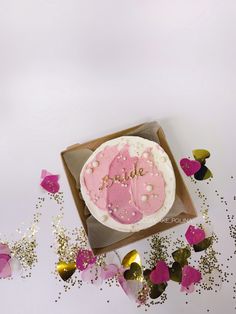 a pink cake sitting on top of a table next to confetti and streamers