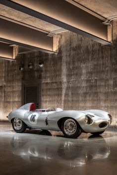 an old silver race car parked in a garage