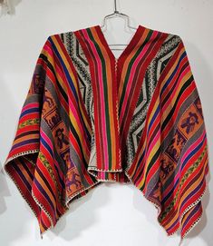 This is a spectacular poncho with its intricate hand stitching,vivid colours, and has the addition of Inka symbols running down each side. The pictures do not do this piece justice. I was significantly impressived with the detailing and am told a piece like this would take many months to weave by hand. A real head turner. Antique ponchos are between 70 to 100 years old. Originally worn by the Q'ero people of the Peruvian Andean mountains. They are hand-knitted with a tight weave to provide water Folk Style Festival Poncho One Size, Traditional One Size Woven Poncho, Traditional Woven Shawl Poncho, Handwoven Festival Poncho Shawl, Traditional Festival Poncho With Woven Motifs, Handwoven Poncho Shawl For Festivals, Handmade Artisan Poncho For Festivals, Traditional Handwoven Poncho One Size, Traditional Handwoven One-size Poncho