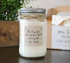 a jar filled with white candles sitting on top of a table next to a box