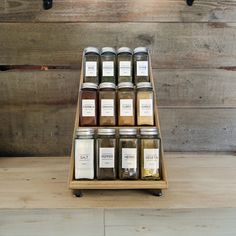 a wooden shelf holding jars filled with different types of spices and seasonings on it