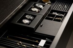 an open drawer with several watches and jewelry in it's compartments on the table