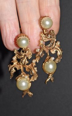 "Fancy Vintage Statement Gold Tone Leaf & Pearl Dangle Screw Back Earrings Stunning dangle gold tone metal earrings. Large faux pearls and tiny faux pearls accent the earrings. They have screw backs. These earrings are unmarked. Earrings are 2\" long x 7/8\" wide. Large pearls are 9mm round. Small pearls are 2.4mm round. Pearls are an off white color. In great pre owned condition. A little discoloration on the gold tone but they look great for their age. Thanks for looking :)" Gold Chandelier Earrings With Pearl Charm For Party, Formal Gold Chandelier Earrings With Pearl Charm, Vintage Gold Earrings With Pearl Charm, Gold Pearl Chandelier Earrings For Evenings, Gold Pearl Clip-on Earrings For Evening, Victorian Gold Pearl Earrings For Evening, Vintage Gold Pearl Clip-on Earrings, Vintage Gold Chandelier Earrings For Anniversary, Gold Vintage Chandelier Earrings For Anniversary