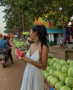 a woman in a white dress holding a watermelon