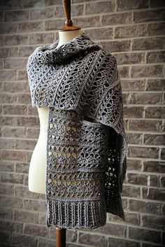 a knitted shawl on a mannequin with brick wall in the background