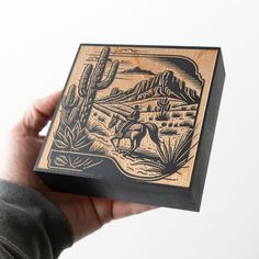 a person holding up a wooden box with an image of a man riding a horse